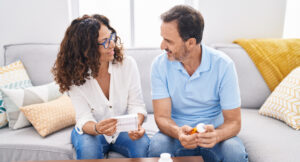 Man and woman holding pills reading prescription