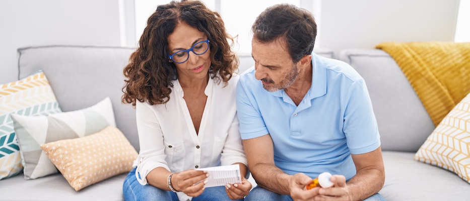 Man and woman holding pills reading prescription